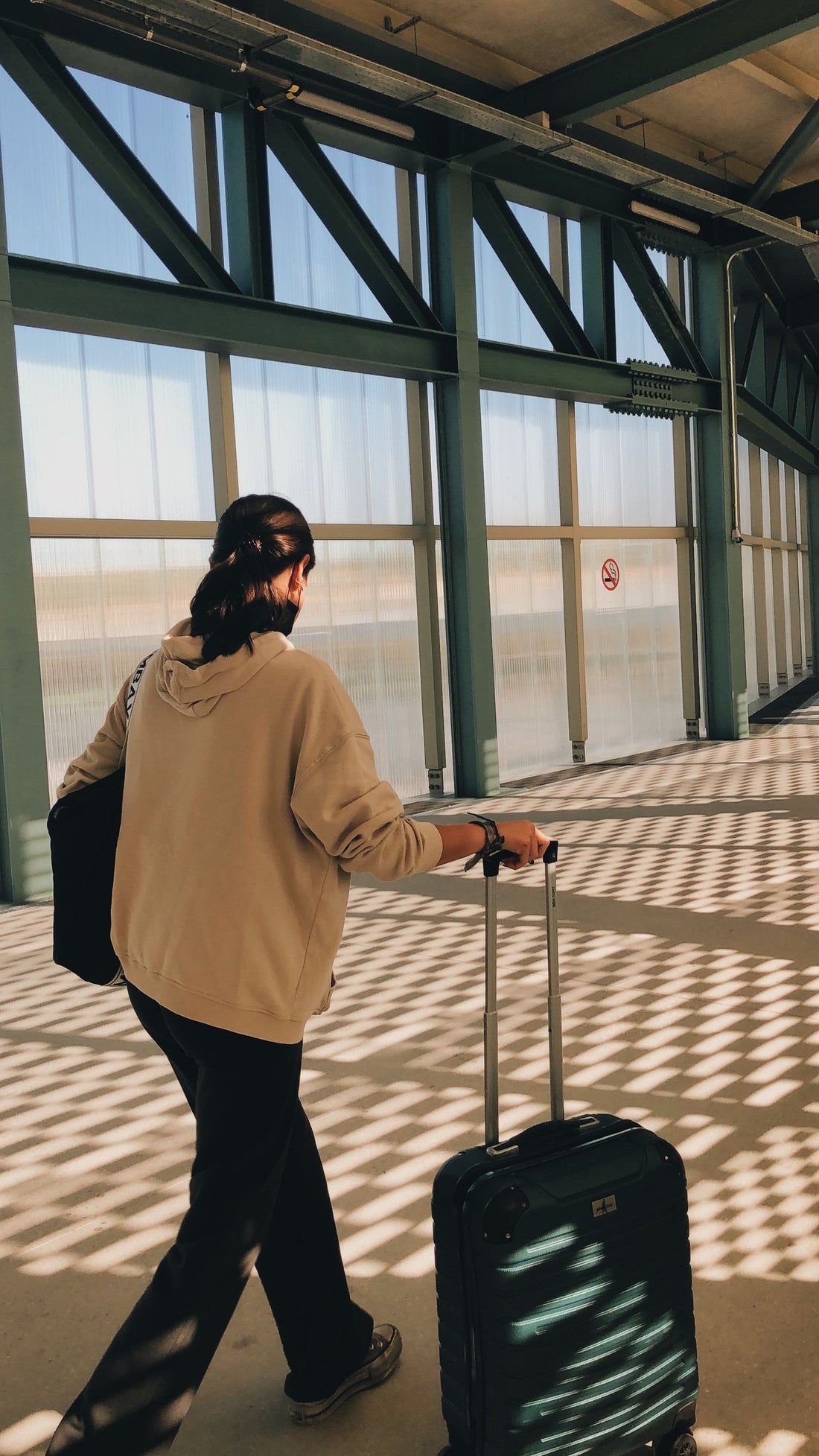 Viajera con maleta de cabina caminando hacia la terminal del aeropuerto